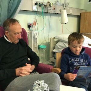 A patient, Dave being read to by his young grandson in the Inpatient Unit